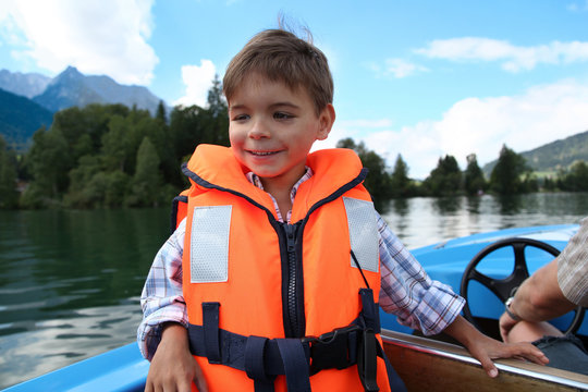 Junge in oranger Schwimmweste an Bord eines Motorbotes