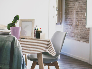 Modern table with flower, photo frame and stationery in cozy flat. Living room interior and home decor concept