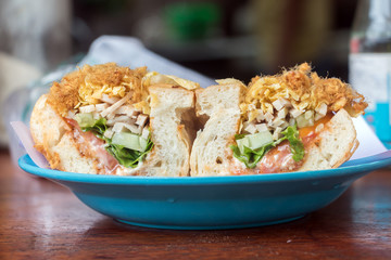 Sandwich stuffed with vegetables, ham and pork threads, served on plate in street restaurant at Luang Prabang, Laos.