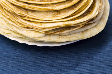 Pancakes for carnival on a plate, blue napkin, traditional food