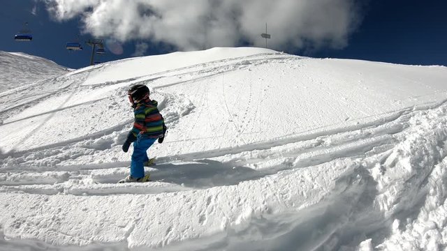 Freeride skiing. Little boy skiing in the wild. A 5 year old child enjoys a winter holiday in the Alpine resort. Stabilized shot. Slow motion.
