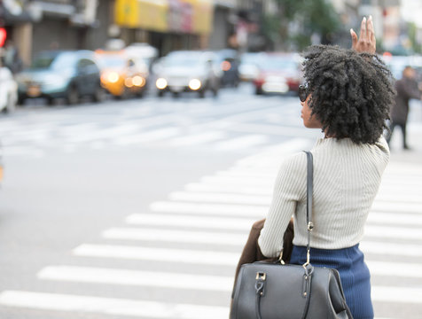 African American Woman hailing a taxi cab on a city street