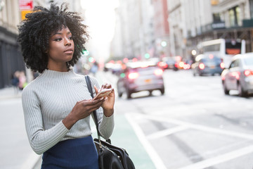 Woman with mobile device waiting for rideshare car service - obrazy, fototapety, plakaty
