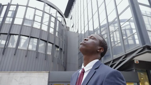 young black businessman in the street looks up,thinking future