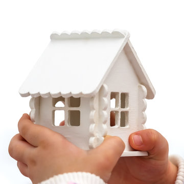 Child's hands is holding a toy house on a white background