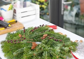 Photo sur Plexiglas Fleuriste Christmas wreath made by professional florist on table in flower shop