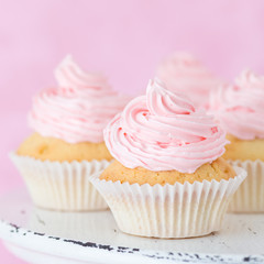 Cupcake decorated with pink buttercream on pastel pink background.