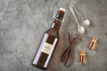 Composition with glass bottles of vanilla extract on grey background, top view
