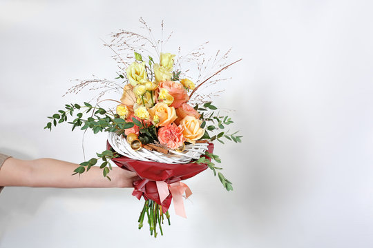 Young florist holding beautiful bouquet on white wall background