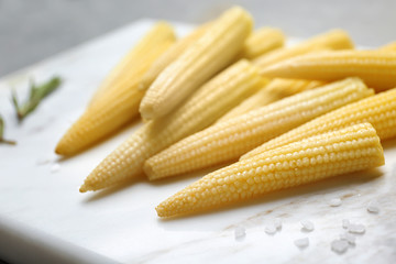 Fresh young baby corn on marble board, closeup