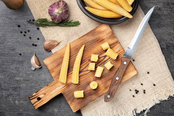 Wooden board with fresh young baby corn on table