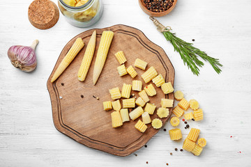 Composition with fresh young baby corn on white wooden background