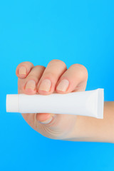 cream advertising, female hand holds the white cream tube with copy space