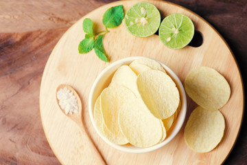 Potato chip in a bowl with spoon of salt and slice lime, top view