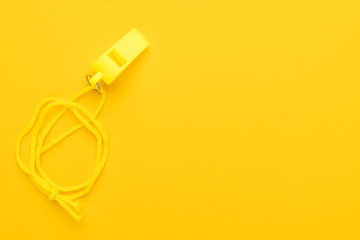 plastic referee whistle on the yellow background with copy space