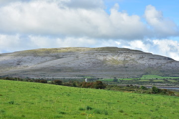 Fototapeta premium Karst landscape of Burren Plateau with fresh green pastures in foreground.