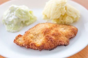 Homemade traditional Polish kotlet schabowy with mizeria and mashed potatoes.