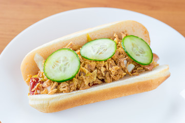 Copenhagen hot-dog with ketchup, mustard, chopped yellow onion. fried onion and sliced green cucumber.