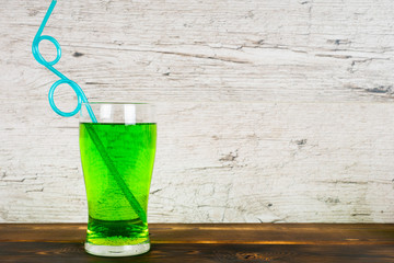 green soft drink with cocktail pipe on rustic table