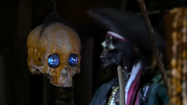 Still-life style background with a skull and a pirate in costume. Blue diamonds sparkle in the darkness in eye sockets. A realistic frightening composition. Thematic horror shooting for halloween