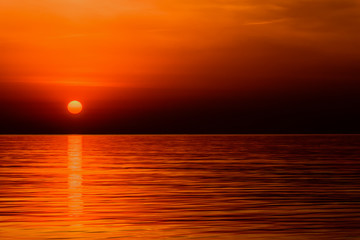 Crimson red sunrise of the orange sun over the ocean