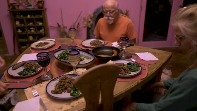 Steadicam orbit around a table while the family sits down and prepares to eat.