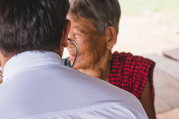 Male Doctor listening heart beat and breathing of Elderly Woman with Stethoscope with First Aid...
