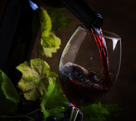 Red wine pouring into a glass, vintage wood background, selective focus