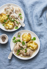 Smashed roasted sage butter potatoes and mustard cream sauce meat - tasty lunch on blue background, top view
