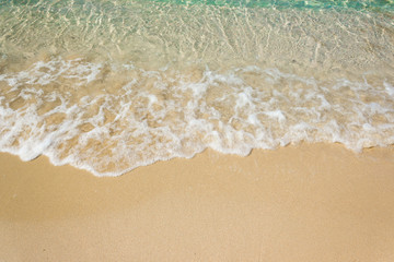 Soft waves with foam of blue ocean on the sandy beach