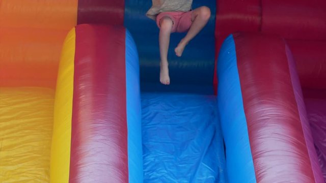 Slow Motion A Girl Slides Down A Huge Inflatable Slide During A Party