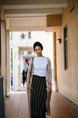 Image of a  Muslim Malay women wearing a stylish blue turban. She is standing in the middle a hallway and she is wearing a very elegant, attractive and professionally dressed.