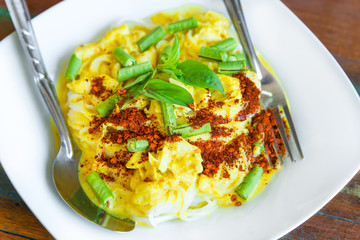 Rice vermicelli in green curry with crab and vegetables with Long bean and hoary basil on wooden table the traditional delicious Thai food.