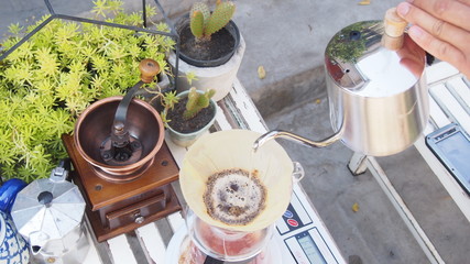 hand drip coffee, barista pouring hot water over roasted grinded coffee powder making drip brew...