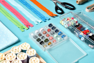 Pastel color background, Dressmaker and designer desk, Handcraft accessories, Threads roll, scissors, zip, button.
