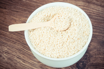 Vintage photo, Heap of sesame seeds in white bowl on wooden board