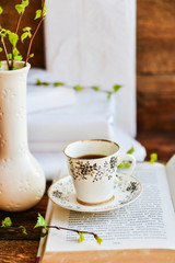 open book, coffee mug, branches with green leaves, the concept of love for reading, spring and freshness