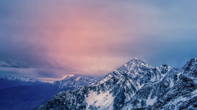 Snowcapped mountains zooming out to reveal a stunning scene with a time lapse animated cloudscape during a dark sunrise or sunset