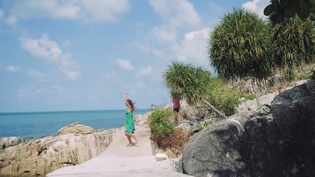 Young attractive brunette happy woman in green prety dress runs near the sea excited and amazed by nature, holidays, summer, vacation. slow motion. 1920x1080