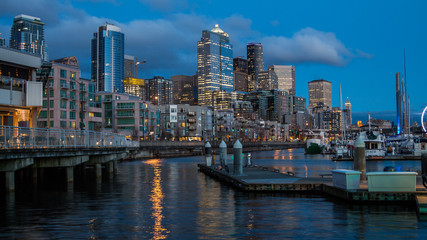 Fototapeta premium Lights reflections from lights of a big city on the water near the pier
