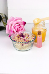 Fototapeta na wymiar homemade scrub with sea salt,aroma oils and rose petals and honey jaerwhite background