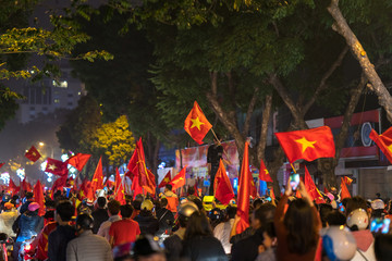 Fototapeta na wymiar Crowd of Vietnamese football fans down the street to celebrate the win after soccer, with a lot of Vietnamese flags raising high