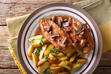 Italian American food: Chicken in Marsala wine with fried mushrooms and potatoes close-up. Horizontal top view