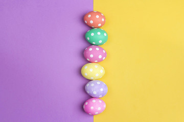 Colored Easter eggs on purple and yellow background. Space for text.