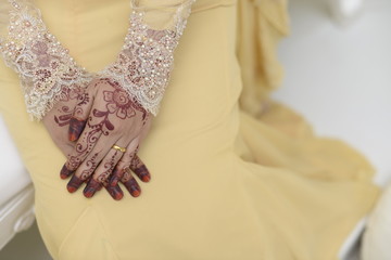 Bride & groom holding hands showing off the beautiful henna art in a Malaysian wedding.