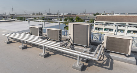Air compressor machine part of air conditioner system on roof deck with sky background.