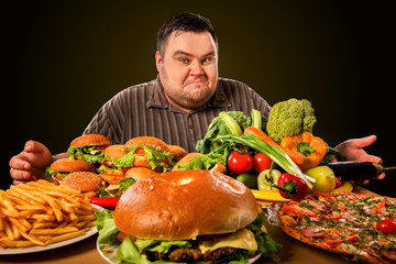 Diet fat man who makes choice between healthy and unhealthy food . Overweight male with hamburgers, french fries. Feast on the occasion of the feast. - 196128744