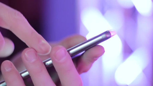 Browsing information on smart at colorful place. Man touch phone and change color. Person use modern gadget in front of beautiful light