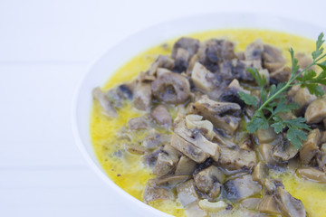 Cooked mushrooms in a white mask on a white wooden background