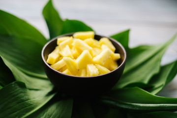 Sliced fresh pineapple in a bowl on the leaves